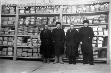 Сотрудники Полоцкого городского Госархива: курьер-уборщица К. Ф. Нестеренко, старший архивариус И. Е. Сахончик, архивариус Т. Д. Белокурова, директор Я. М. Печенкин в архивохранилище (1958 г.) Белорусский государственный архив кинофотофонодокументов. 0-061818.